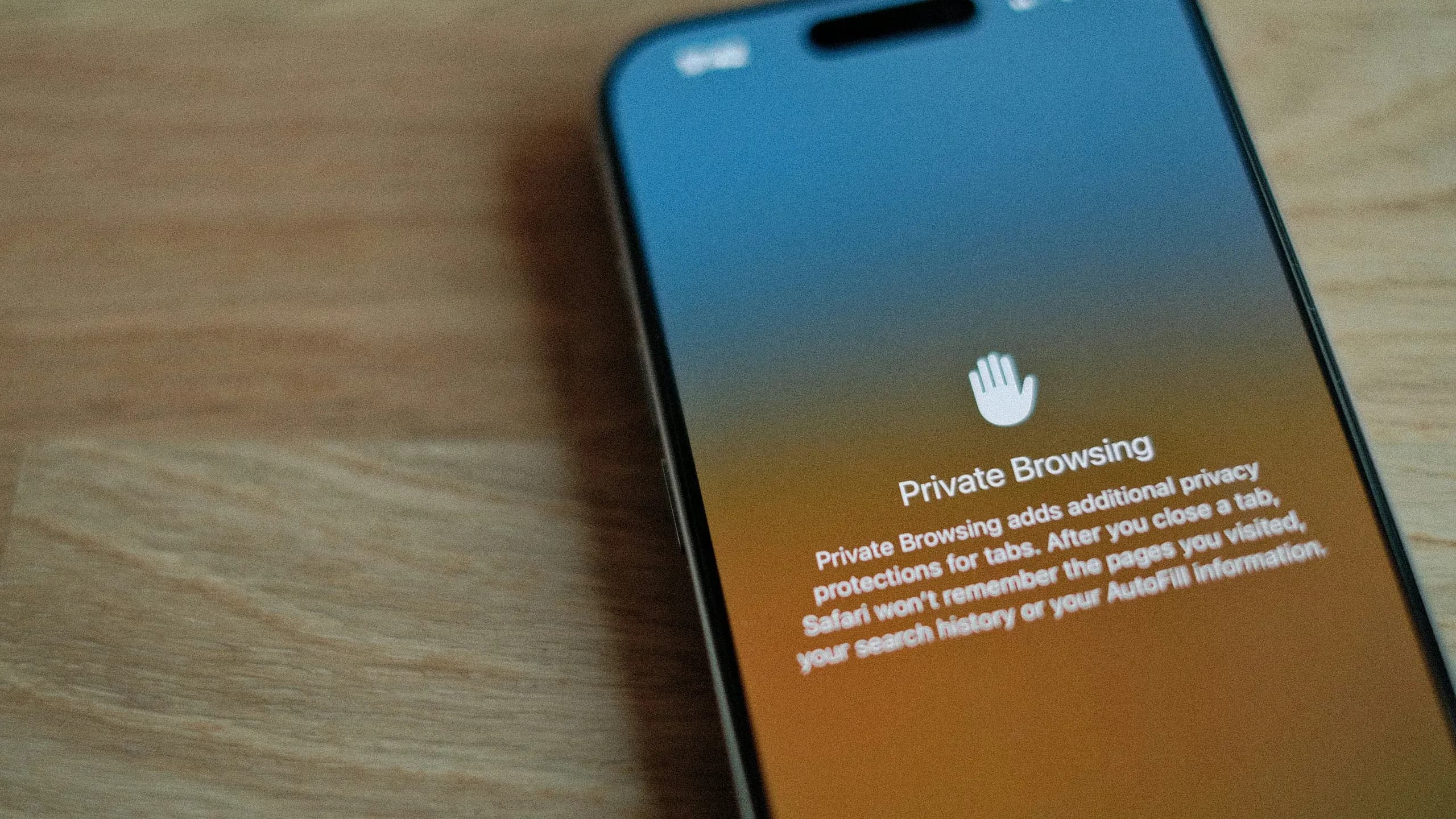 A phone lying on a wooden table, its screen showing a browser’s private browsing notice